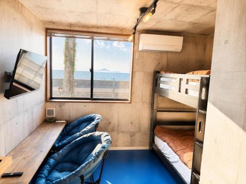 a room with bunk beds and a desk and a window at 江田島BASE in Okimi in Etajima