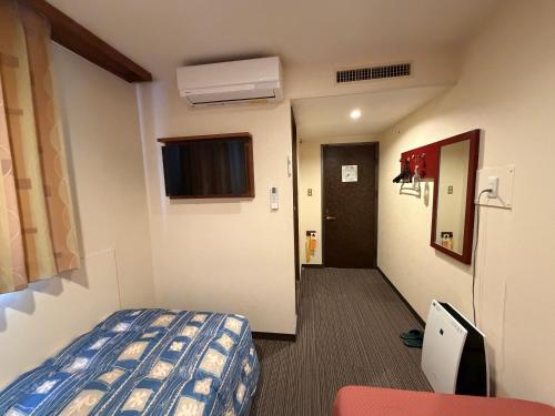 una camera d'albergo con un letto e un corridoio di Hotel Ikeda a Nagasaki