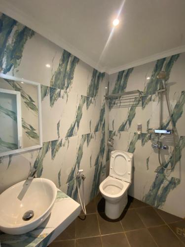 a bathroom with a white toilet and a sink at Hotel Paris Santika in Rawara