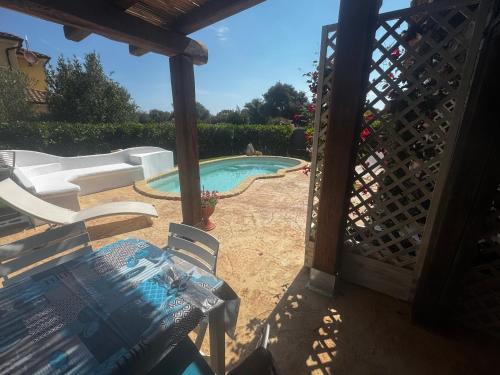 a patio with a table and chairs and a swimming pool at Casa Vacanza Li Menduli San Teodoro in San Teodoro