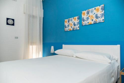 a blue bedroom with a white bed and a blue wall at Appartamento Sunny by ThePuglia in Torre Lapillo