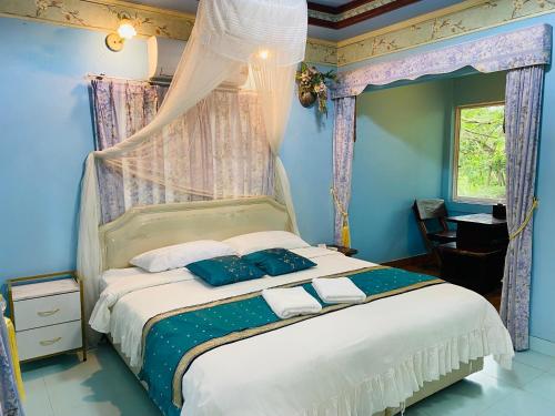 a bedroom with a bed with blue walls and curtains at Saiyok River House in Sai Yok