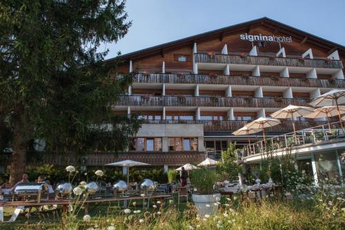 a hotel with tables and umbrellas in front of it at signinahotel in Laax