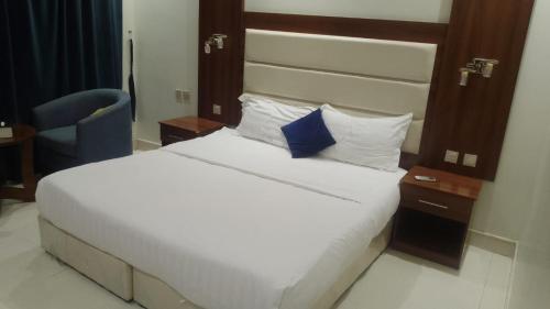 a bedroom with a large bed and a blue chair at فرس ابها - شقق مفروشه in Abha
