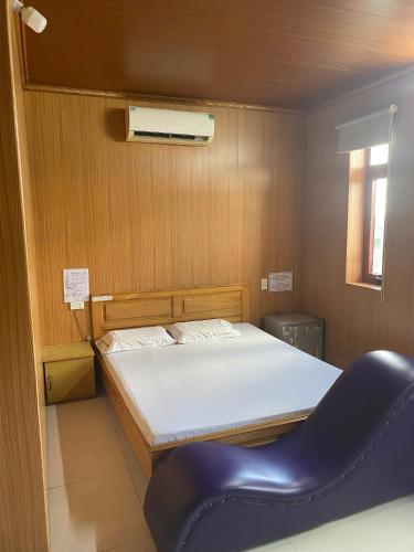 a bedroom with a bed and a blue chair at khách sạn gia bình in Xóm Miếu