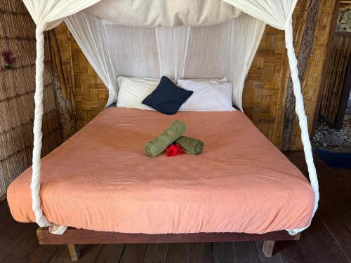 a bed with a canopy with two pillows and a red blanket at Fireworks Tree House in White Sands