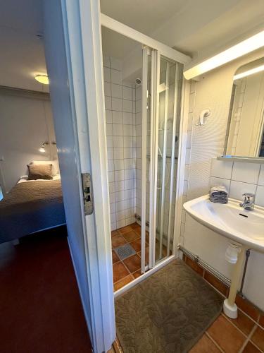 a bathroom with a sink and a shower and a bed at Hällestrand Semesterby R19 in Strömstad
