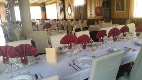 un comedor con mesas blancas y sillas con servilletas rojas en Hotel Gardu, en Montealegre del Castillo