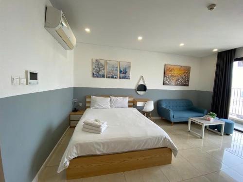 a bedroom with a bed and a blue couch at Vinhomes D'Capitale - Amee Apartment in Hanoi