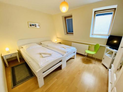 a bedroom with a white bed and a green chair at Ferienhaus Jan in Warnemünde