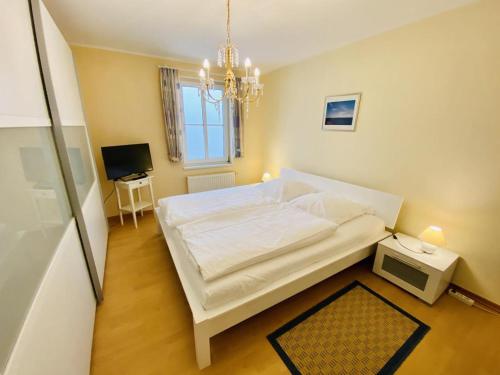 a bedroom with a large white bed and a chandelier at Ferienhaus Adele in Warnemünde