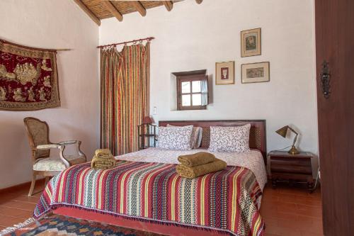 a bedroom with a bed and a chair and a window at Montes de Baixo in Odeceixe