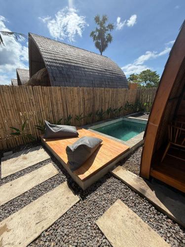 a swimming pool with two pillows on a wooden deck at Kokonut Resor Amed in Amed