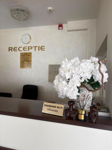 a reception desk with a vase of flowers on a counter at Hotel Parc in Craiova