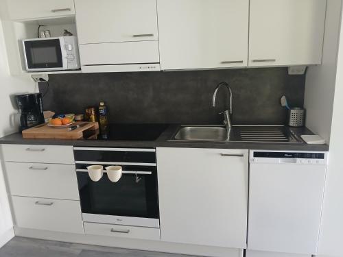 a kitchen with white cabinets and a sink at Cozy Studio Järvenpää in Järvenpää