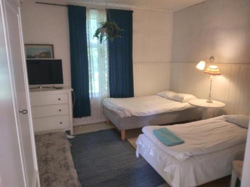 a hotel room with two beds and a television at Ruissalo Cottage in Turku