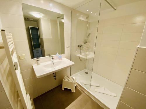 a white bathroom with a sink and a shower at Landhaus Immenbarg, Alter Strom in Warnemünde