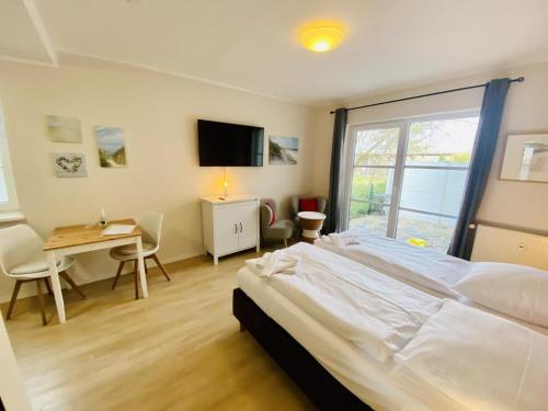 a bedroom with a large white bed and a desk at Landhaus Immenbarg, Lobby in Warnemünde