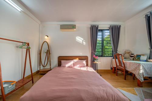 a bedroom with a bed with pink sheets and a table at Live like a local Homestay in Ấp Tư Tây