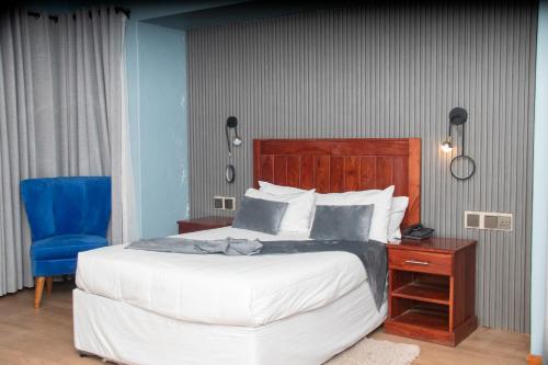 a bedroom with a large bed and a blue chair at Hotel Redcliff in Redcliff