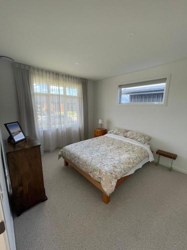a white bedroom with a bed and a window at Modern home, old charm! in Lake Hāwea