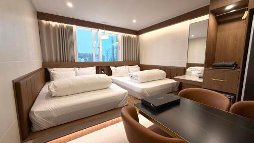 ein Hotelzimmer mit zwei Betten und einem Schreibtisch in der Unterkunft Urban Brown Hotel in Gunsan
