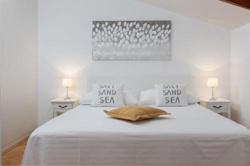 a bedroom with a white bed with two lamps at Apartment Amfora in Podgora