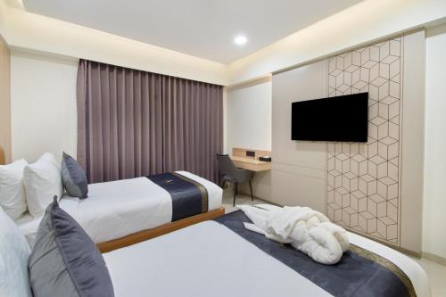 a hotel room with two beds and a television at Hotel V Kondapur in Hyderabad