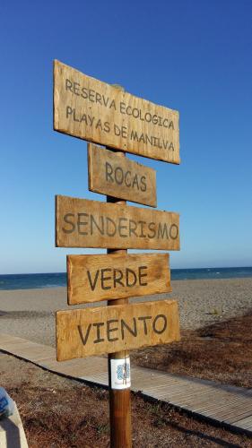 a wooden sign on the beach with several signs at Manilva Beach 97 in Manilva
