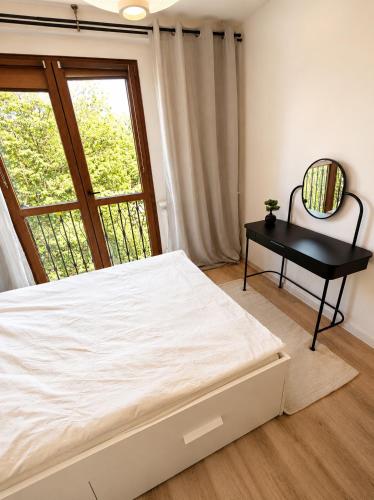 a bedroom with a bed and a table and a window at Zielone drzwi in Żywiec