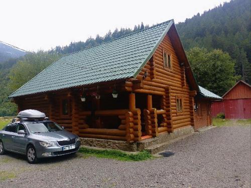 a log cabin with a car parked in front of it at Котедж Перша Хата in Synevyrsʼka Polyana