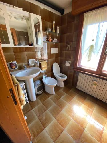a bathroom with a sink and a toilet and a window at La Casa del SEI SERIO in Pieve di Cadore