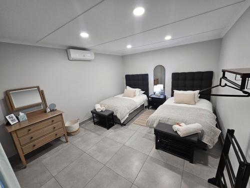a bedroom with two beds and a dresser and a mirror at Rosa's Self-catering in Springbok
