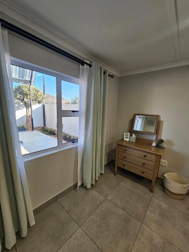a room with a window and a mirror on a dresser at Rosa's Self-catering in Springbok