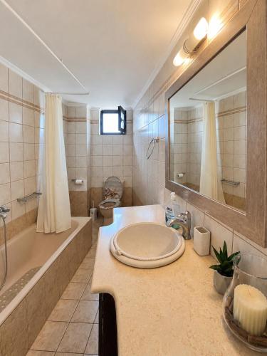 a bathroom with a sink and a tub and a mirror at Dimitris house in Parga
