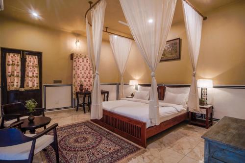 a bedroom with a canopy bed with curtains at Garrison at Dera Bagseu in Bikaner