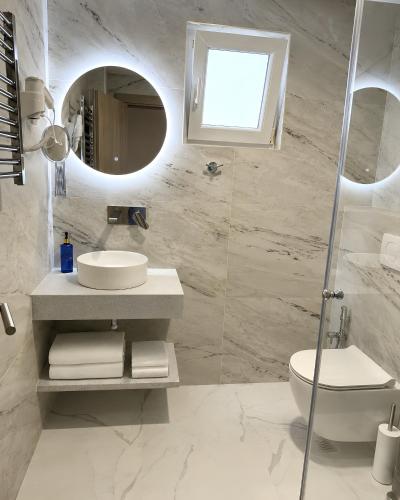 a white bathroom with a sink and a mirror at Hotel Fineso in Budva