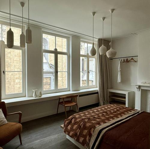 a bedroom with a bed and a desk and windows at guesthouse 't Kleihuys in Bruges
