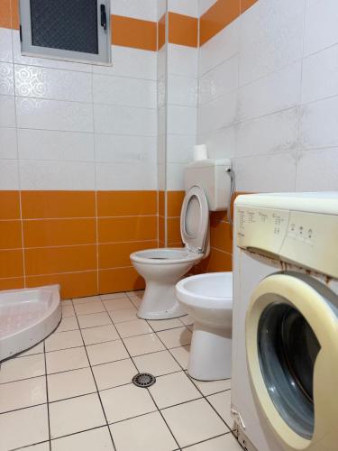 a bathroom with a toilet and a washing machine at AS Orikum 2 in Orikum