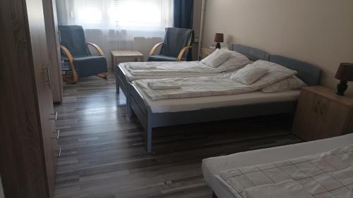 a bedroom with two beds and two chairs and a window at Panel Hause Kazincbarcika in Kazincbarcika