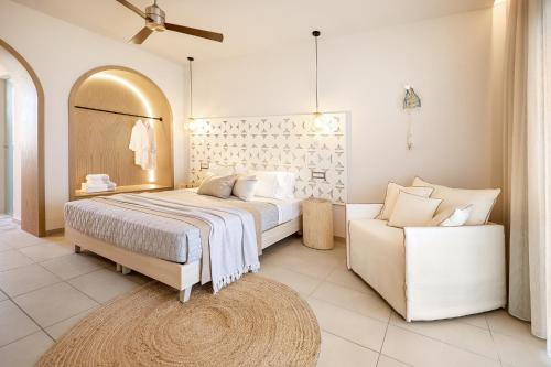 a white bedroom with a bed and a couch at Maravel Star Art Hotel in Adelianos Kampos