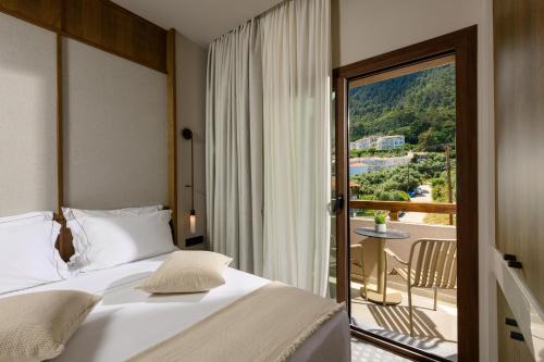 a bedroom with a bed and a view of a balcony at Enavlion Elegance Seaside Luxury in Chrysi Ammoudia