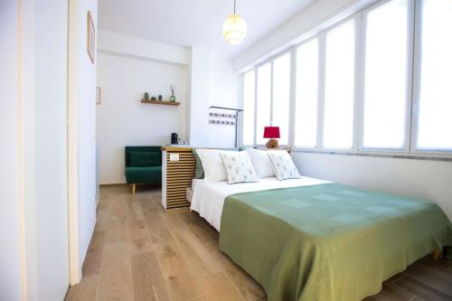a white bedroom with a bed with a green blanket at Pole Pole - NATURA in Agropoli