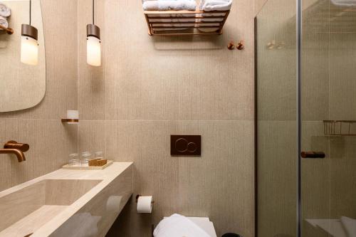 a bathroom with a shower and a sink and a toilet at Enavlion Elegance Seaside Luxury in Chrysi Ammoudia