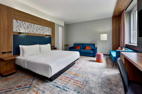 a hotel room with a bed and a blue couch at Aloft by Marriott Munich in Munich