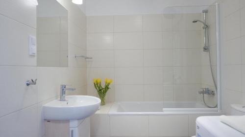 a white bathroom with a sink and a bath tub at Apartament Biały in Darłówko