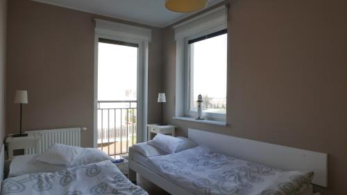 a bedroom with two beds and a window at Apartament Biały in Darlowko