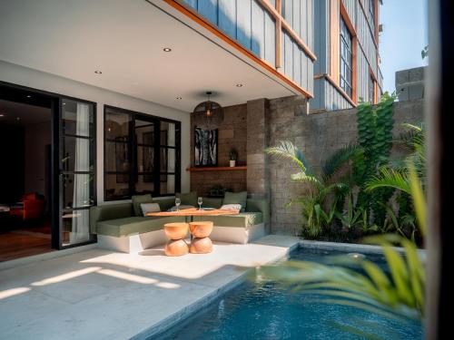 a living room with a couch and a table next to a pool at Secana Beachtown Resort & Villas in Canggu