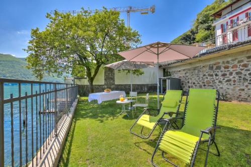 a patio with chairs and a table and an umbrella at 76 The Lake House - Lugano in Melide