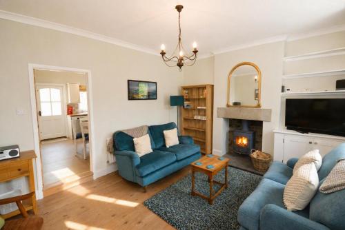 a living room with a blue couch and a fireplace at Brookfield Cottages in Bakewell